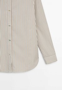 Chemise à manches longues boutonnée avec des rayures verticales marron et blanches, montrant le devant et la manche droite sur un fond blanc.