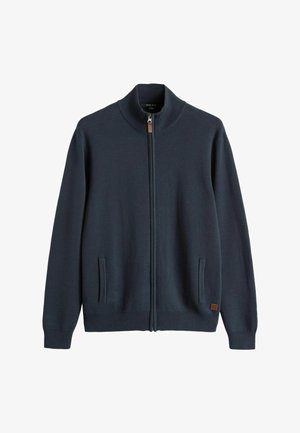 Mørkeblå zip-up sweater med ribbede krave og manchetter, sidelommer og et lædermærke nær sømmen. Glat strikket tekstur.