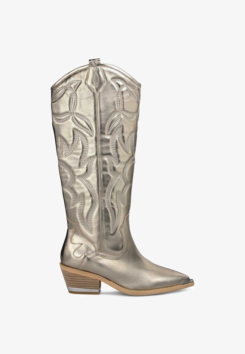 Bota vaquera plateada metálica con punta afilada, costuras decorativas y un tacón bajo y apilado. Presenta un patrón embosado elaborado.
