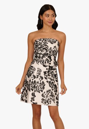 Schulterfreies schwarz-weißes Blumenkleid mit tailliertem Oberteil und weit ausgestellt Rock. Der Stoff zeigt aufwendige Blumenmuster und eine strukturierte Oberfläche.