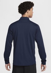 Camisa polo de manga larga en color navy con cuello clásico, textura suave y construcción sin costuras, vista desde atrás.
