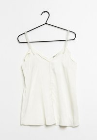 Witte mouwloze top met een V-hals, gemaakt van soepele stof, voorzien van parelaccenten op de bandjes en zijslits. 