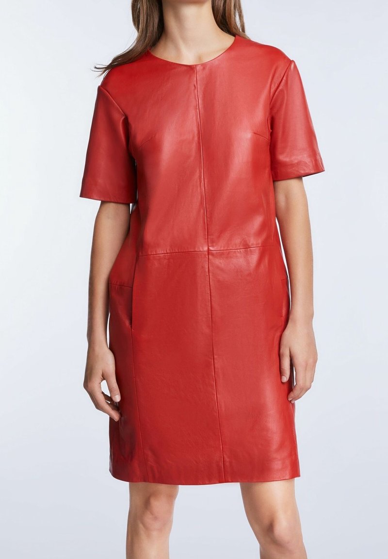 Robe en cuir rouge à manches courtes, col rond et coupe décontractée. Présente des coutures visibles et des poches sur les côtés. Texture lisse.