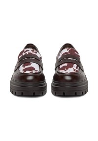 Par čevljev mokasink temno rjave barve z debelimi podplati in vzorcem kravljega usnja v beli in rjavi barvi na zgornjih sprednjih delih.