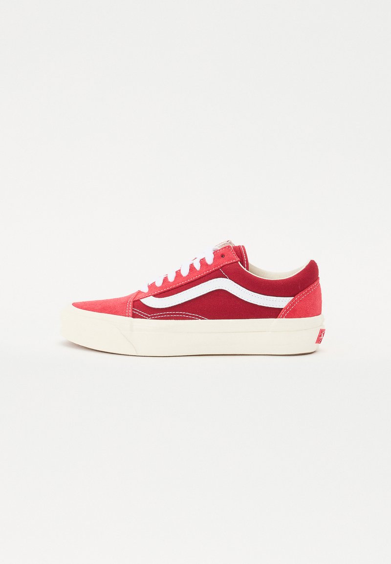 Red canvas sneakers with white accents, flat laces, padded collar, and a thick cream rubber sole. Side features a signature wave design.