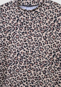 Tkanina w wzór lamparta z beżowym tłem i czarnymi oraz brązowymi plamami. Miękka tekstura o gładkim wykończeniu, idealna na odzież.