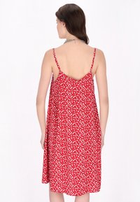 Rochie florală roșie cu buline albe, bretele subțiri ajustabile și croială lejeră. Material ușor și design cu spate în formă de V.