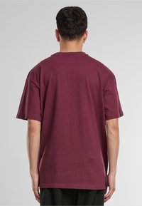 Burgundy cotton t-shirt with a relaxed fit, round neck, and short sleeves, featuring minimalistic design and smooth texture.
