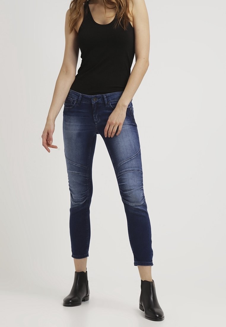 Jeans i denim med en mörkblå gradient och urblekta accenter. Har sömnad vid knäna och en slim fit. Kombineras med en svart linne och ankelskor.