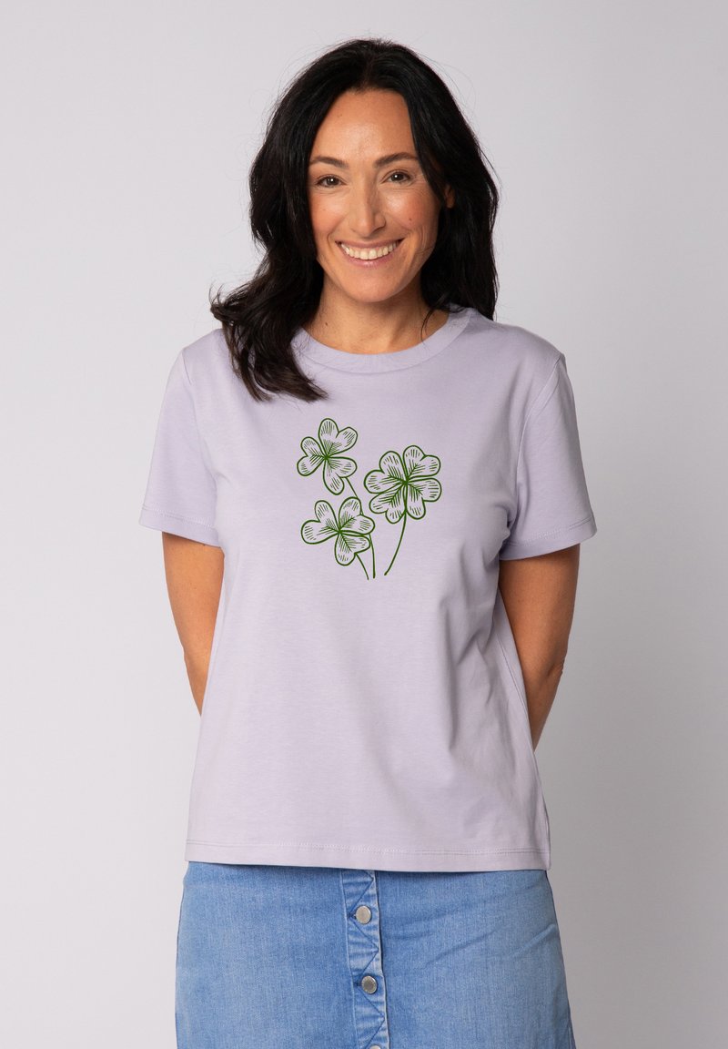 Lila katoenen t-shirt met een groene illustratie van drie klavertjes op de voorkant, met een klassieke ronde hals en korte mouwen.
