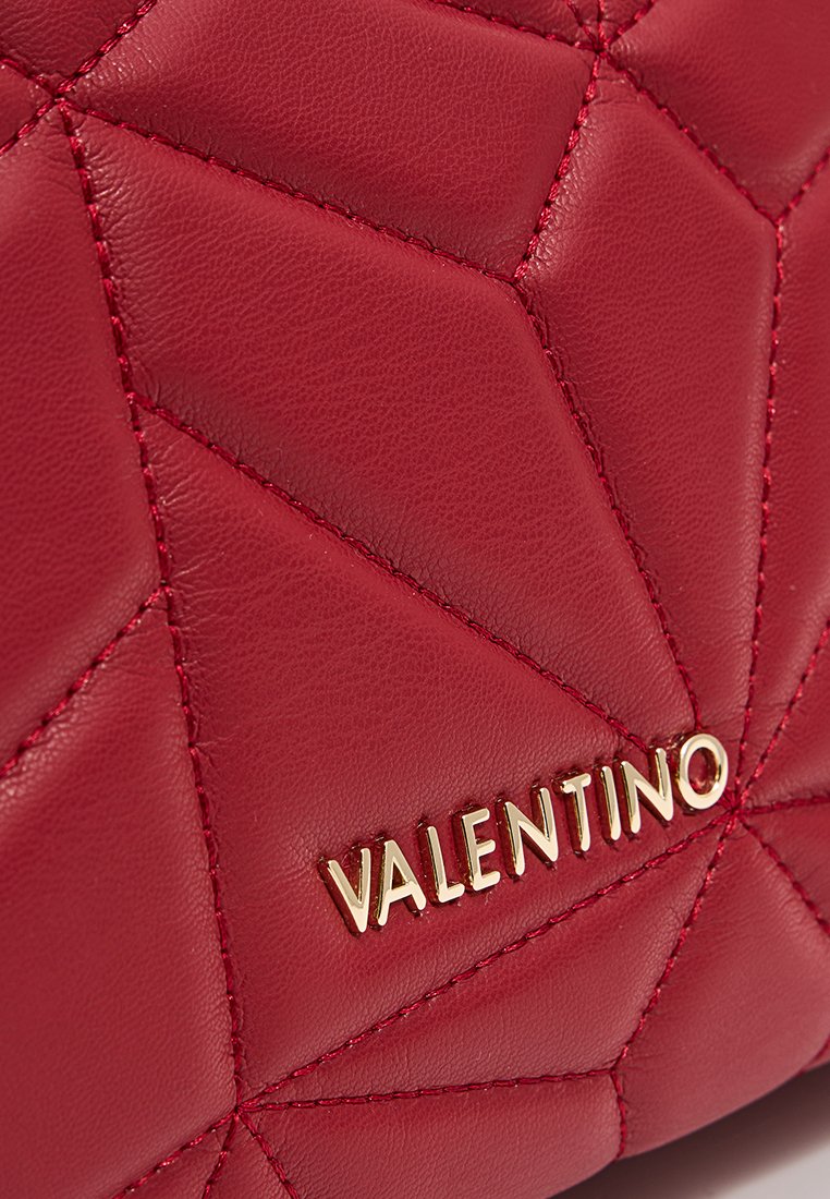 Sac en cuir rouge présentant un motif géométrique matelassé, avec un accent en or et des détails de couture raffinés, mettant en avant une texture lisse.