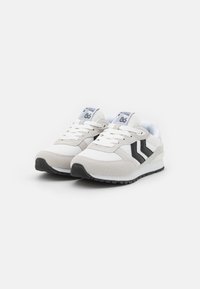 Ljust grå sneakers med svarta accenter, i en kombination av mesh och mockamaterial, platta snören och en texturerad gummisula.