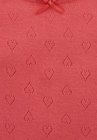 Korálovoružová pletená látka s malými dierkovanými srdiečkami a malou korálovou mašličkou v hornej strede.