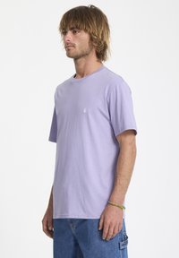 Kortærmet lyse lilla bomuld t-shirt med rund halsudskæring og lille logodetalje på brystet. Afslappet pasform og glat tekstur.