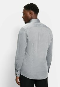 Gray patterned button-up shirt with a spread collar, long sleeves, and black button accents on cuffs. Tailored fit with a slight sheen.