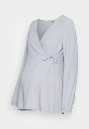 Top envolvente lilás claro com mangas longas, fecho por laço na cintura e uma silhueta fluida, elaborado em tecido suave.