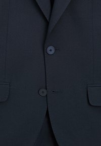 Ciemnogranatowa marynarka o teksturowanej tkaninie, z dwoma czarnymi guzikami i pojedynczą kieszenią na piersi oraz ostrymi klapami.