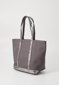 Pilkas drobės prekybos maišelis su sidabriniais metaliniais dirželiais ir akcentais, stačiakampio formos, su dviem tvirtomis rankenomis, turintis tekstūruotą apačios apdailą.