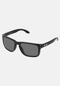 Ochelari de soare negri cu un cadru din plastic gros, lentile gri închis și accente metalice subtile pe brațe. Formă pătrată cu textură netedă.