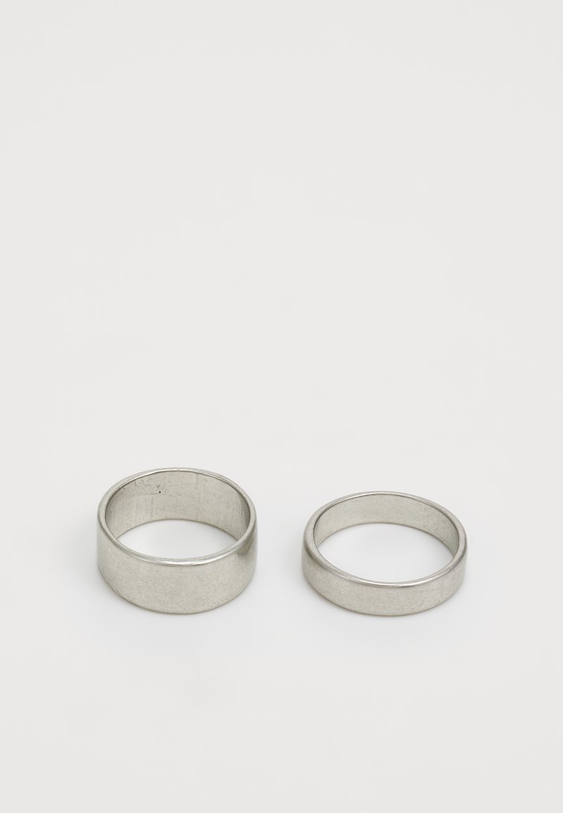 Two metallic rings, one wider and one slimmer, both featuring a smooth, polished finish and a matte silver color on a plain white background.