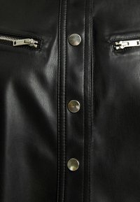 Czarna skórzana kurtka z srebnymi akcentami, w tym zamkami błyskawicznymi i zatrzaskami, o teksturowym wykończeniu i pionowych detalach szwów.