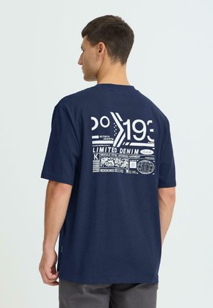 Marineblå bomulds t-shirt med korte ærmer, med hvidt grafisk tryk på ryggen, inklusive tal og mærkater. Rette snit med sideslidser.