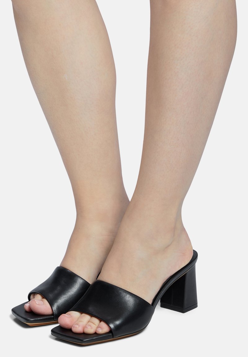 Zwarte leren haksandalen met een vierkante open teenontwerp en een stevige blokhak. Gladde textuur met minimale detailing.