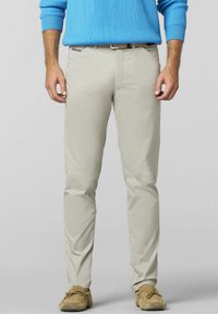 Helle beige Chinos im Slim Fit, mit vorderen Taschen und subtilen Steppdetails. Kombiniert mit einem strukturierten blauen Pullover.