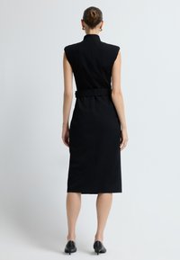 Czarna sukienka bez rękawów z wysokim kołnierzem, z paskiem w talii i długości midi. Gładki materiał z dopasowanym krojem i bocznym rozcięciem u dołu.