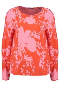 Blusa a maniche lunghe di un vivace arancione con motivi floreali rosa. Presenta un colletto arrotondato e una texture leggera e liscia.