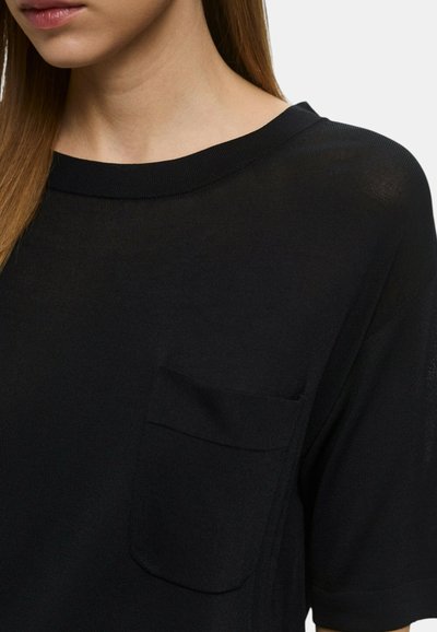 T-shirt nera a maniche corte in un tessuto morbido e leggero, con collo rotondo e una tasca sul lato sinistro del petto.