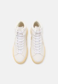 Visoke tenisice od bijele kože s kontrastnim bež detaljima, s bijelim vezicama i teksturiranim gumenim potplatom.