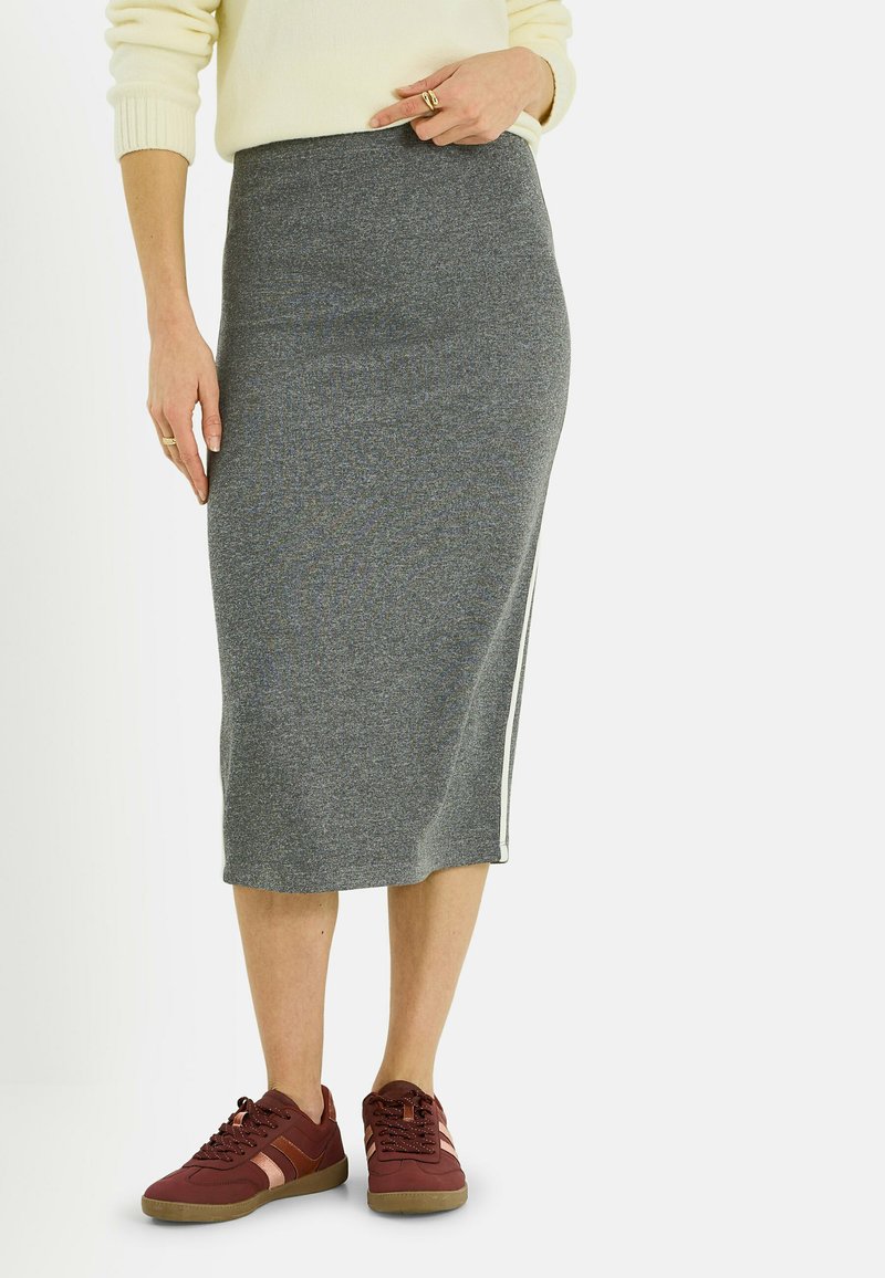 Falda midi de punto gris con ajuste ceñido y abertura lateral, combinada con zapatillas burdeos. La tela tiene un aspecto texturizado y un diseño cómodo.