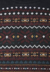 Strickstoff mit horizontalen Bändern geometrischer Muster in dunklem Rot, Schwarz, Weiß, Gelb und Blau.