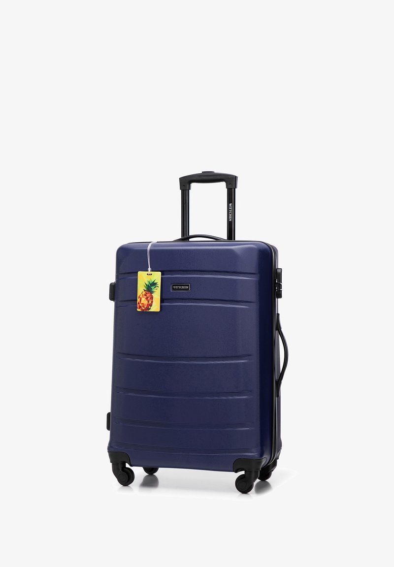 Marineblauwe koffer met een harde schaal en een gestructureerde afwerking, zwarte wielen en een uitschuifbare handgreep. Inclusief een bagagelabel met een ananas-thema.