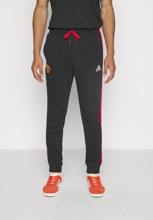 Schwarze Sweatpants mit roten Seitenstreifen, mit einem Manchester United-Logo und weißem Adidas-Logo. Verstellbarer roter Kordelzug, gerippte Bündchen.