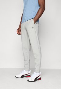 Lys grå joggers lavet af blødt materiale, med slim fit, sidelommer og et subtilt Puma-logo på venstre lår.
