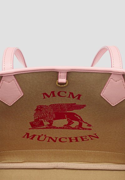 Interno della borsa marrone con rifinitura rosa, con il logo rosso MCM München e grafica del leone alato.