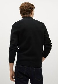 Schwarzer Pullover mit langen Ärmeln, gerippten Bündchen und Saum, aus strukturiertem Stoff. Trägt dazu dunkle Jeans aus Denim, Ansicht von hinten.