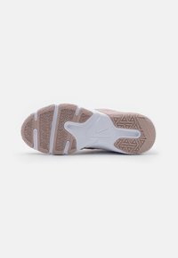 La suela de la zapatilla Nike presenta una base de goma en marrón claro con patrones de agarre texturizados, complementada por una media suela blanca y detalles del logotipo.