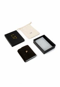 Portafoglio in camoscio nero con finiture dorate, posizionato su uno sfondo bianco. Include una scatola regalo nera e una sacca beige con coulisse.