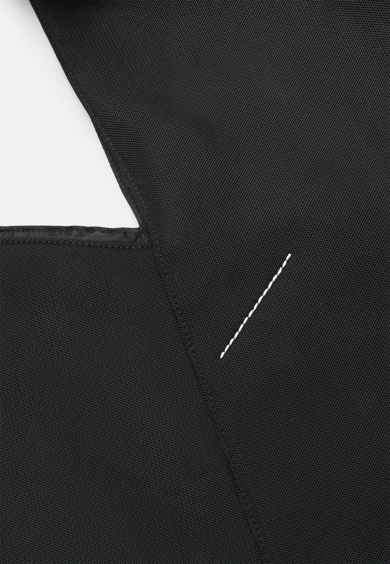 Tejido negro con textura de malla, con un detalle de costura blanca. El diseño incluye un corte asimétrico con un borde suave.