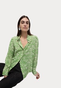 Groen en wit gestreepte button-up shirt van lichtgewicht stof, met een kraag en een losse pasvorm. Gekozen met donkere jeans.