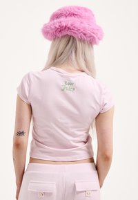 Rózsaszín, rövid ujjú, rövidített póló, melynek hátulján zöld hímzéssel "Love Juicy" felirat olvasható. Puha pamut anyagból, hozzáillő nadrággal párosítva.