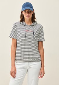 Pasiasty hoodie z krótkim rękawem w białym i granatowym kolorze z czerwonym napisem. Posiada sznurek i elastyczny dół. Noszony z białymi spodniami i niebieską czapką.