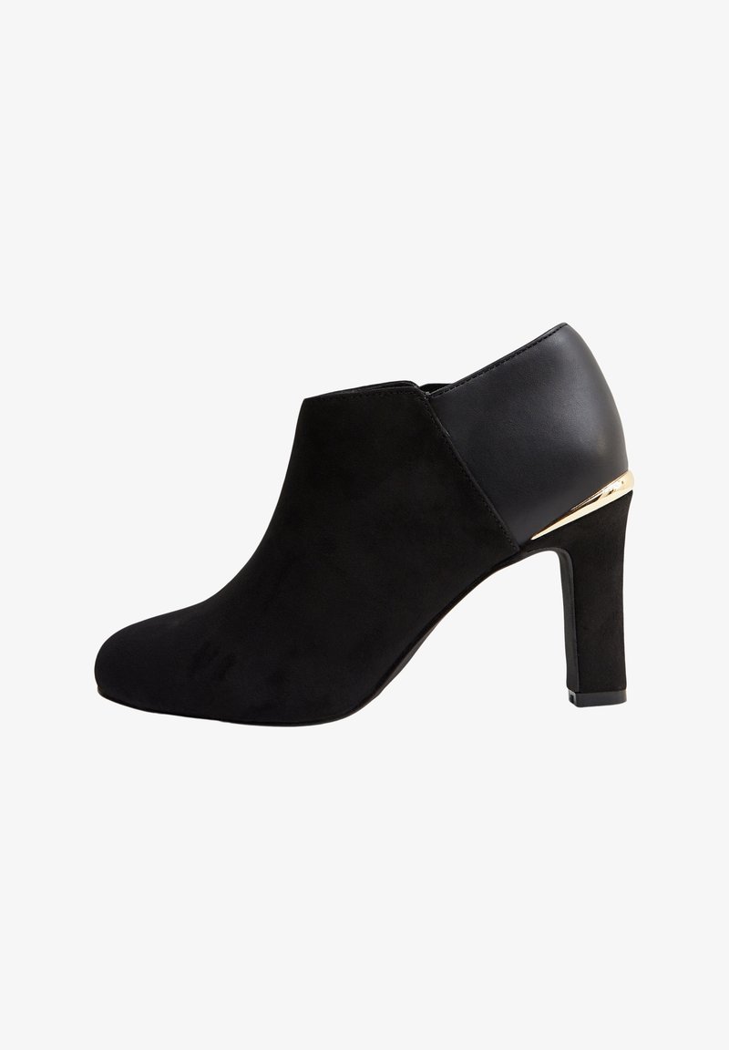 Bottine pour femmes en daim et cuir noir avec un talon bloc et un accent doré au col du talon, présentée en profil latéral sur fond blanc.