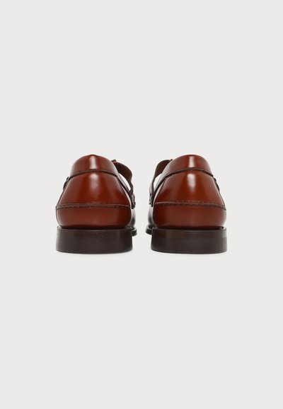 Paire de chaussures de ville en cuir brun poli vues de dos avec semelles foncées sur fond blanc uni.