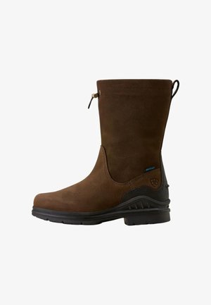 Botte imperméable marron mi-mollet avec semelle en caoutchouc noir, talon renforcé et fermeture par cordon en haut.