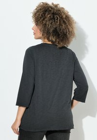 Donkergrijze, lange mouwen shirt met een ontspannen pasvorm en ronde halslijn, vervaardigd van een lichtgewicht, gestructureerde stof en met 3/4 mouwen.