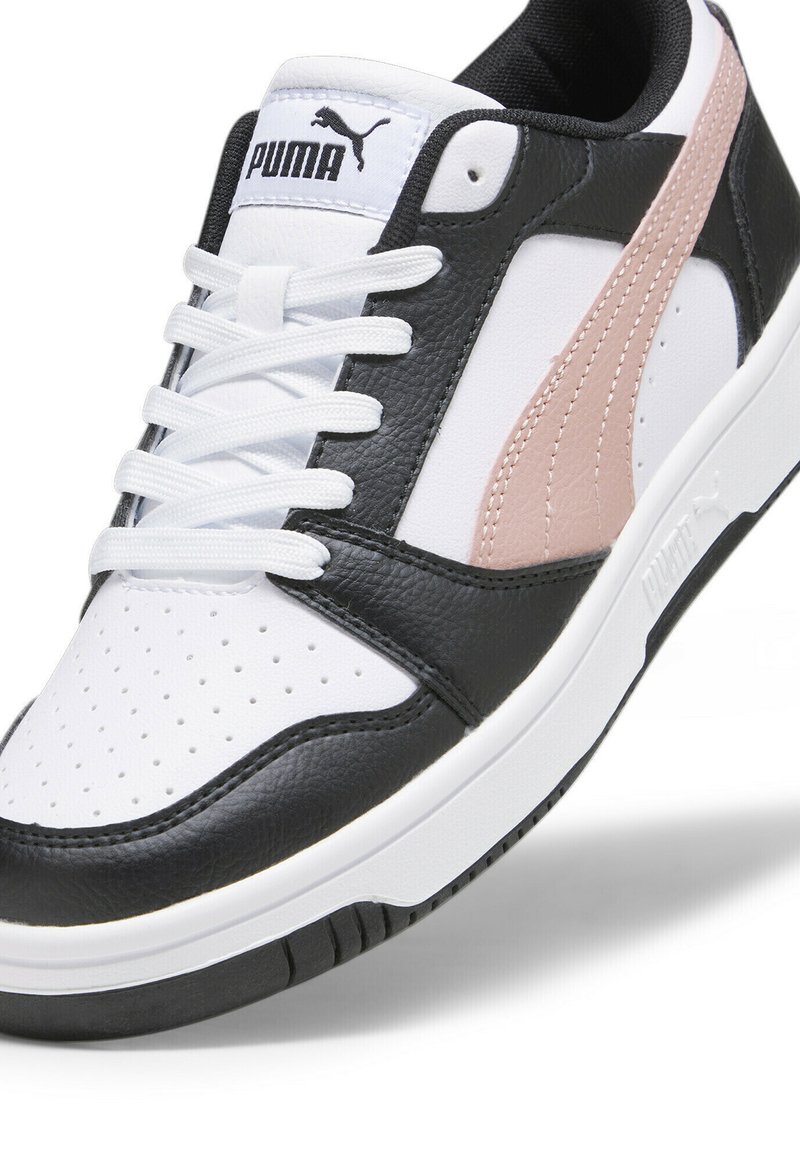 Baskets en noir et blanc avec des accents roses, comprenant du cuir blanc perforé, des côtés texturés noirs et une languette de marque, ainsi qu'une semelle en caoutchouc texturé.